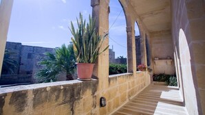 A covered outdoor balcony with stone columns, potted plants, and a view of the cityscape. - Charming Retreat: experience rustic elegance in this beautifully converted fh. (Santa Lucija)