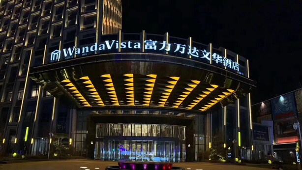 A hotel entrance with a modern design, featuring a curved facade and illuminated signage. - Wanda Vista Changchun (Changchun)