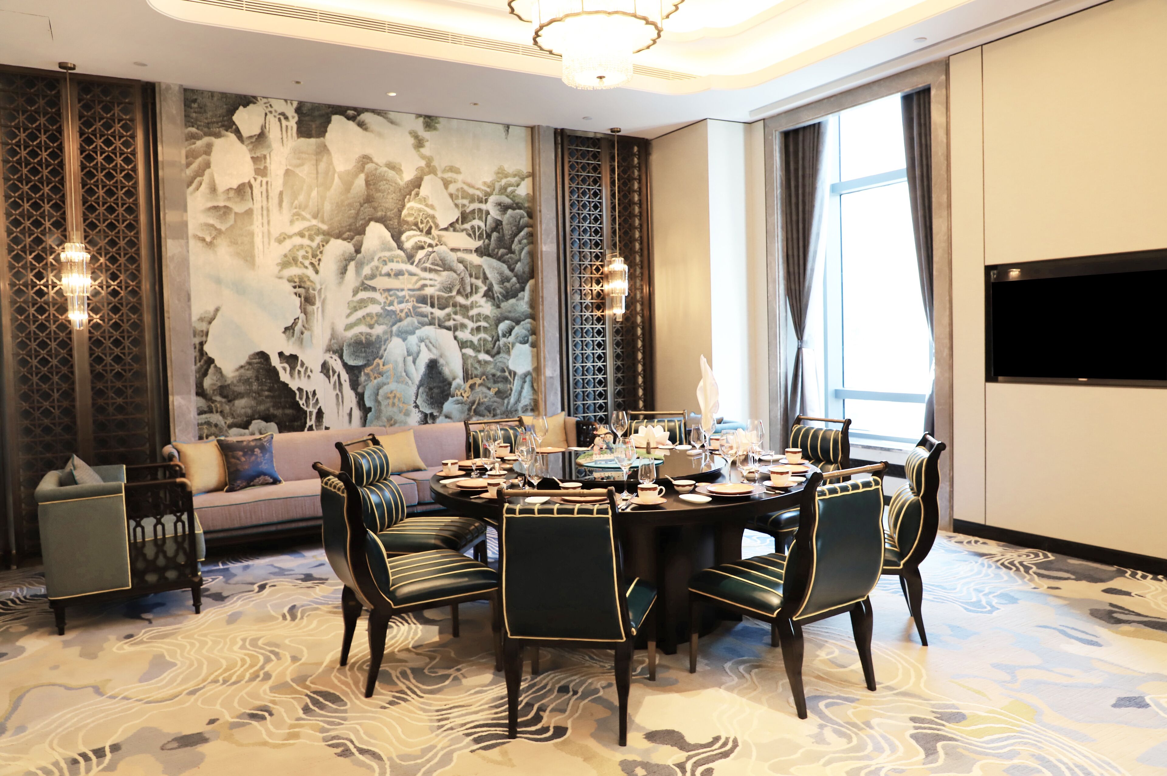 Un comedor con una mesa redonda, sillas y un mural grande en la pared.