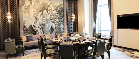 Un comedor con una mesa redonda, sillas y un mural grande en la pared.