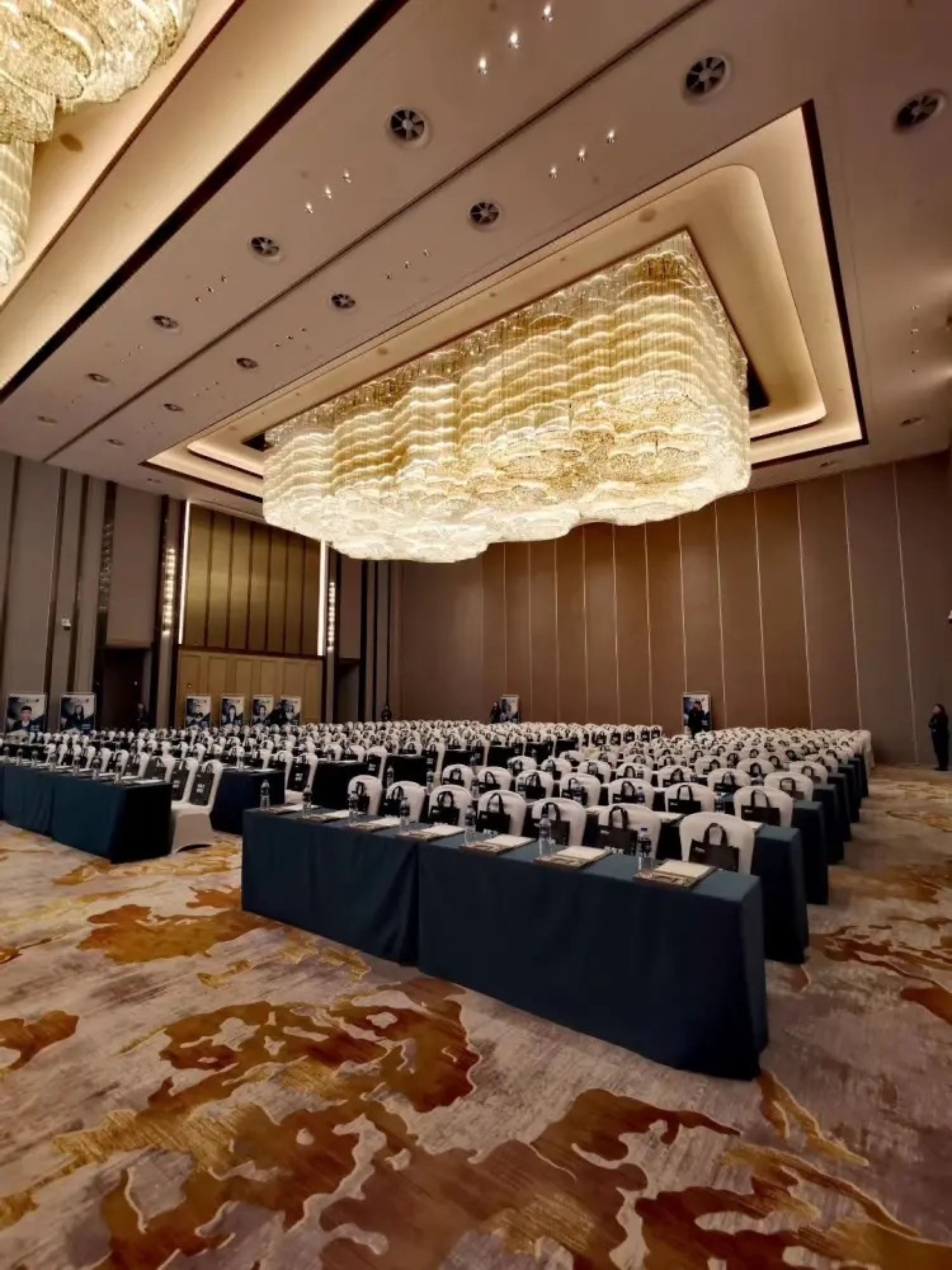 A large conference room with rows of tables, each with nameplates and water bottles.