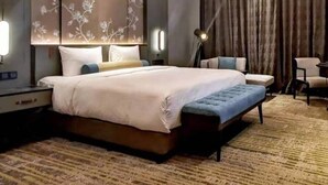 A modern hotel room with a large bed, a desk, a chair, and a lamp. - Wanda Vista Changchun (Changchun)