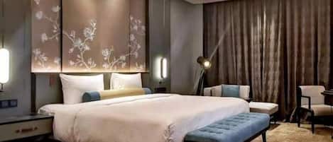 Una habitación de hotel moderna con una cama grande, un escritorio, una silla y una lámpara.