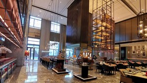 A spacious hotel lobby with a high ceiling, large windows, and a central decorative fountain. - Wanda Vista Changchun (Changchun)