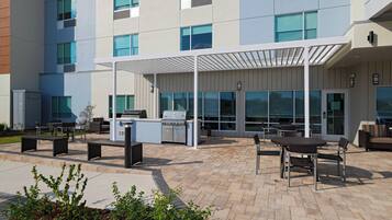 An outdoor patio area with a grill, seating, and a covered walkway.