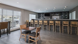 Une cuisine moderne dotée d’un coin bar, de grandes fenêtres et d’un espace repas avec des chaises et une table.