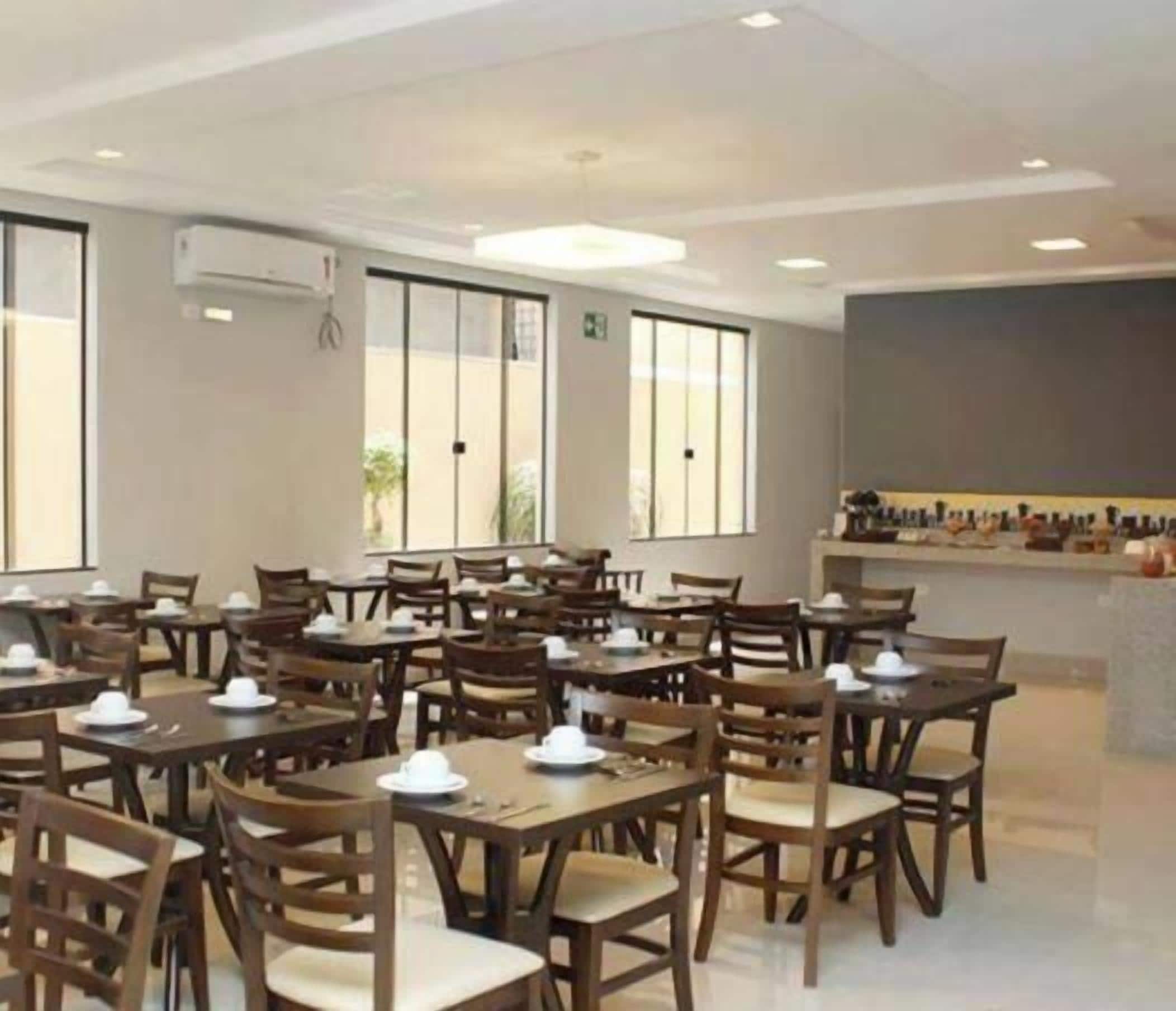 Un espace repas comprenant plusieurs tables et chaises, de grandes fenêtres et un appareil de climatisation fixé au mur.