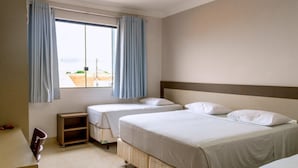 A hotel room with two single beds, a small desk, and a window with curtains. - Hotel Cadori (Paicandu)