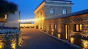 A stone building with a paved driveway and string lights. - Hotel Villa Flora Relais (Caltanissetta)