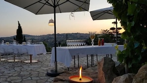 An outdoor dining area with tables set for two, a candle, and umbrellas providing shade. - Hotel Villa Flora Relais (Caltanissetta)