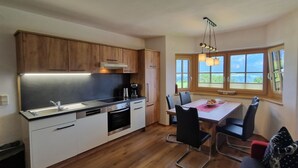 Una cocina moderna con armarios de madera, horno empotrado y comedor con mesa y sillas.