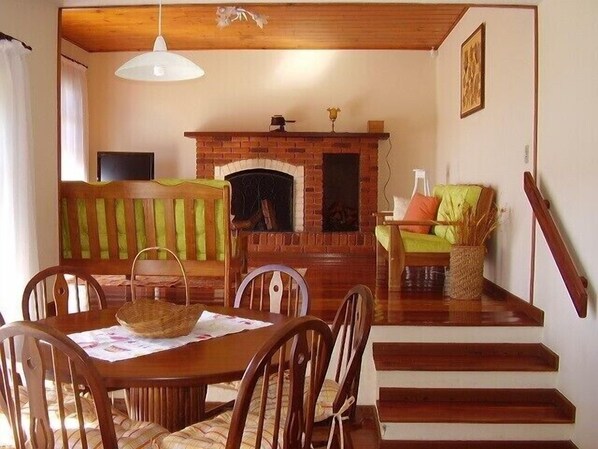 A cozy living room with a brick fireplace, wooden furniture, and a staircase.