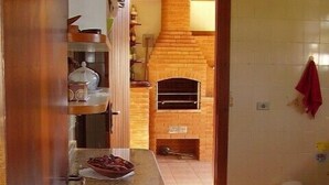 A kitchen with a brick oven, a wooden counter, and a red towel hanging on the wall.