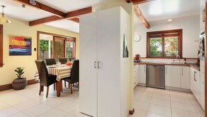 Una cocina moderna con armarios blancos, lavavajillas de acero inoxidable y ventana con vista a follaje.