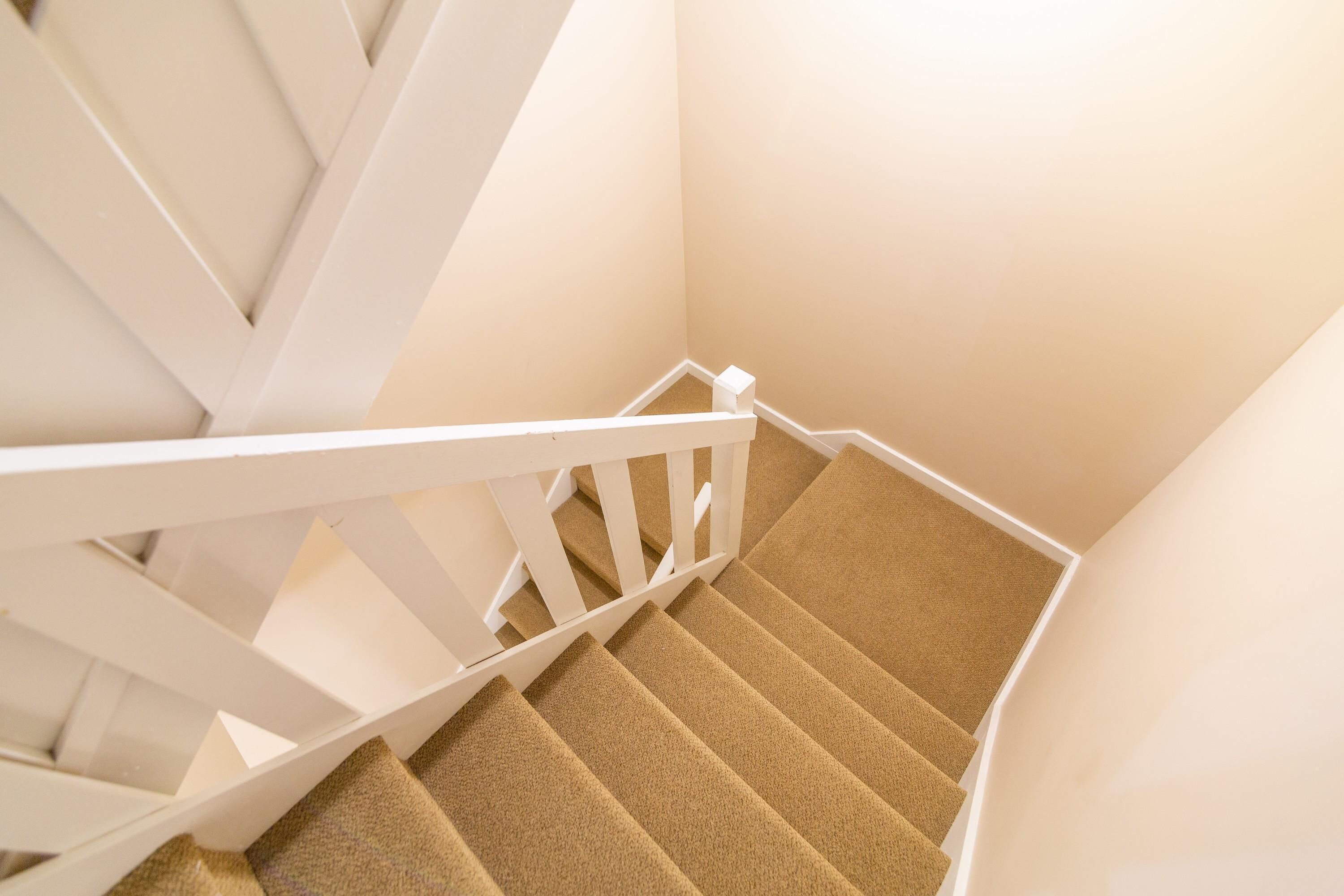 A staircase with white railings and beige carpeted steps.