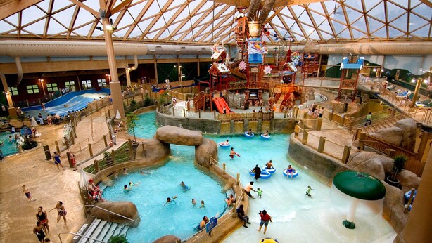 An indoor water park with multiple pools, slides, and water play areas.