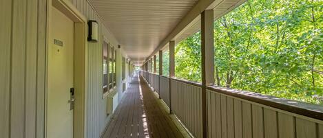 A covered corridor with a wooden floor and white walls, leading to a door marked "2301A".