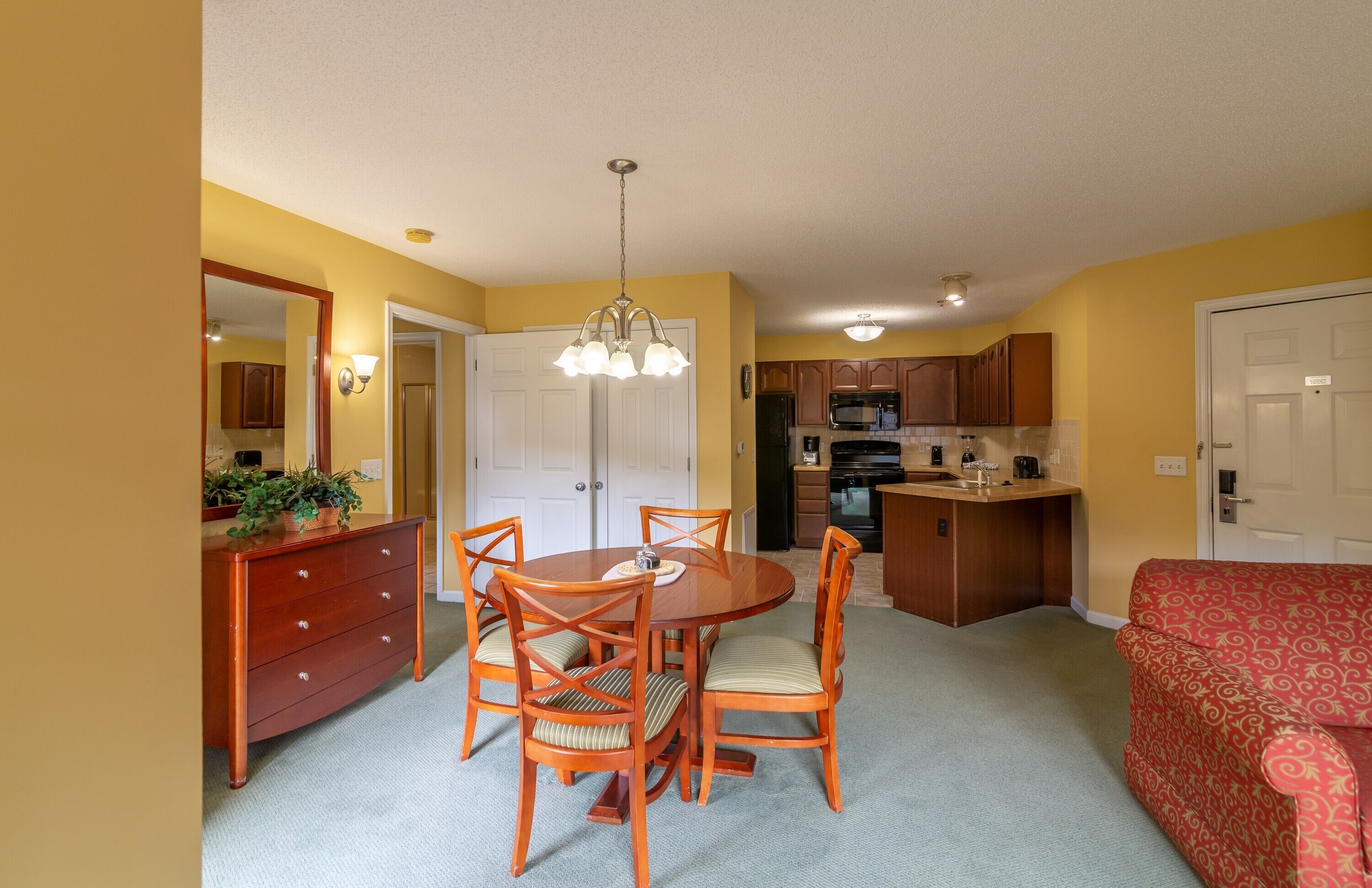 A compact living space with a dining area, kitchenette, and a sofa.
