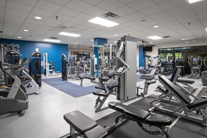 Un gimnasio con diversos equipos de ejercicio, como cintas de correr y máquinas de pesas.