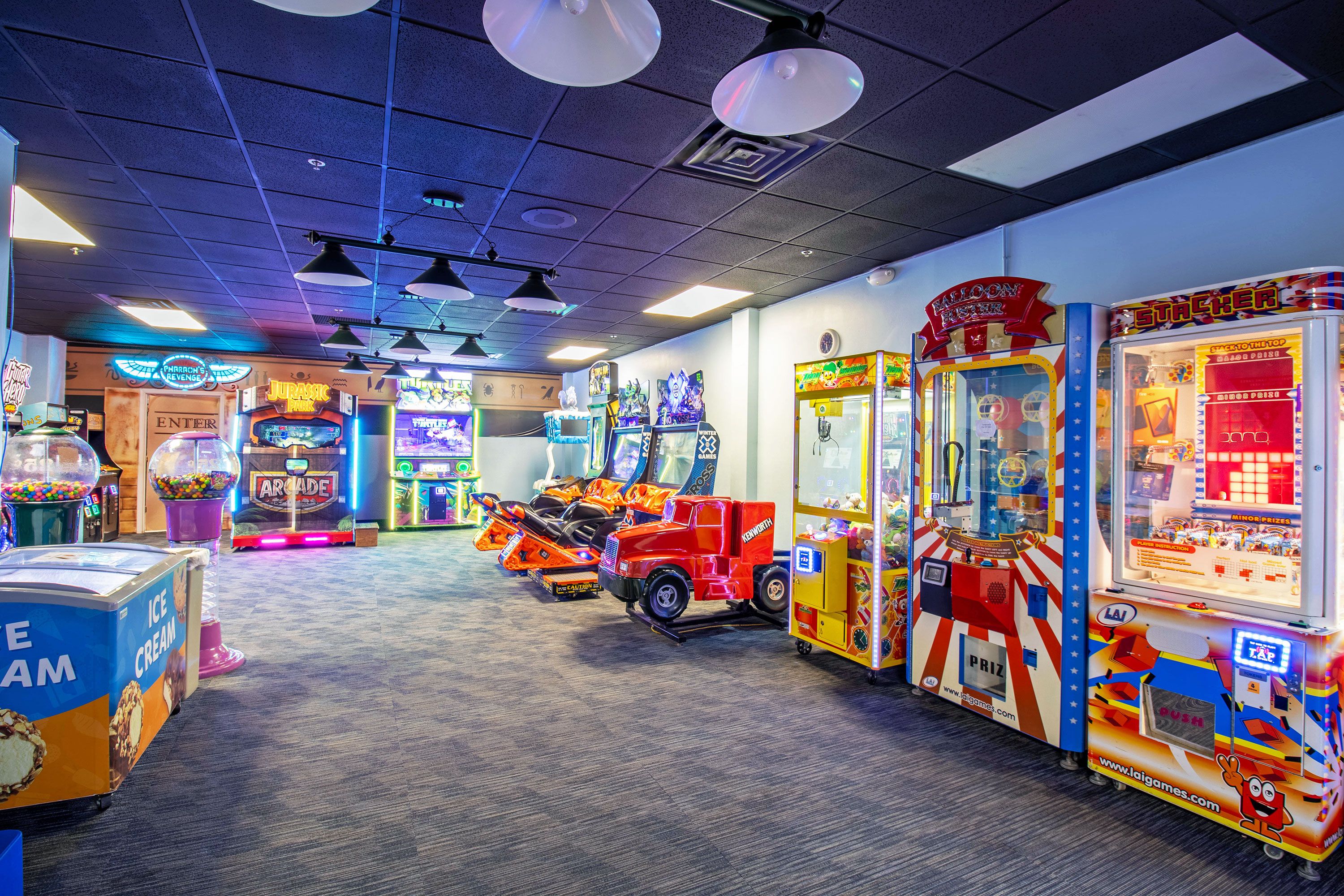 An indoor arcade with various gaming machines, including a red truck game and claw machines.