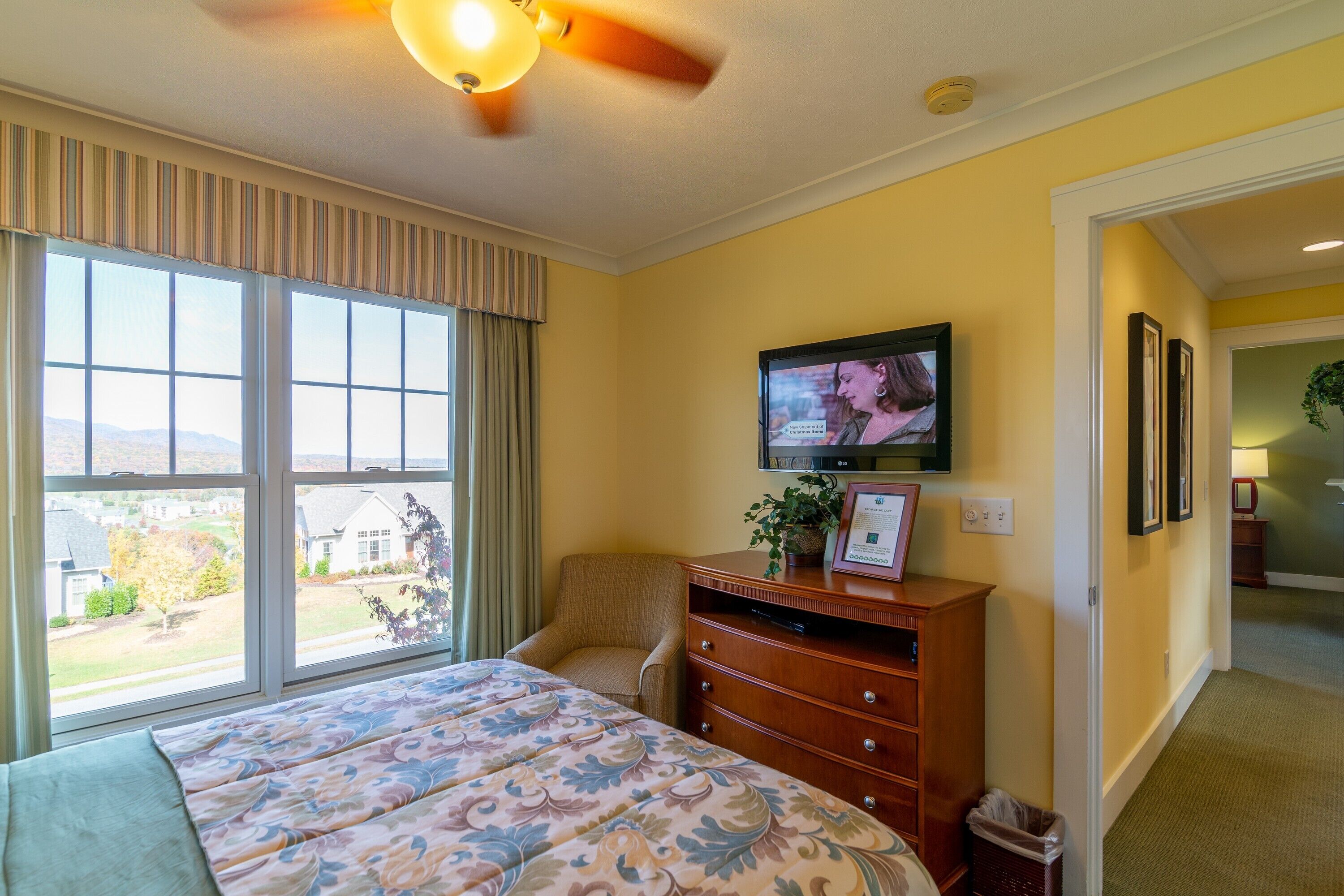 A hotel room with a large bed, a television, a chair, and a dresser.