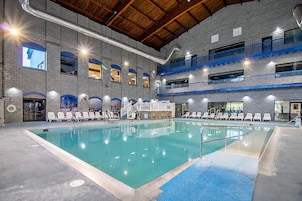 Una piscina interior con varios niveles de balcones, un muro de ladrillo y una zona de piscina despejada.