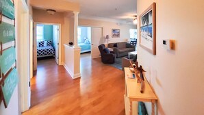 Ein geräumiger Wohnbereich mit Holzdielen, einer Couch, einem Couchtisch und einem Gemälde an der Wand.