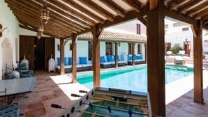 Ein Poolbereich mit Tischfußball, Sitzgelegenheiten im Freien und Blick auf den Pool.