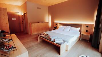 Un dormitorio con suelo de madera, una cama, mesitas de noche y un banco con una bandeja de comida.