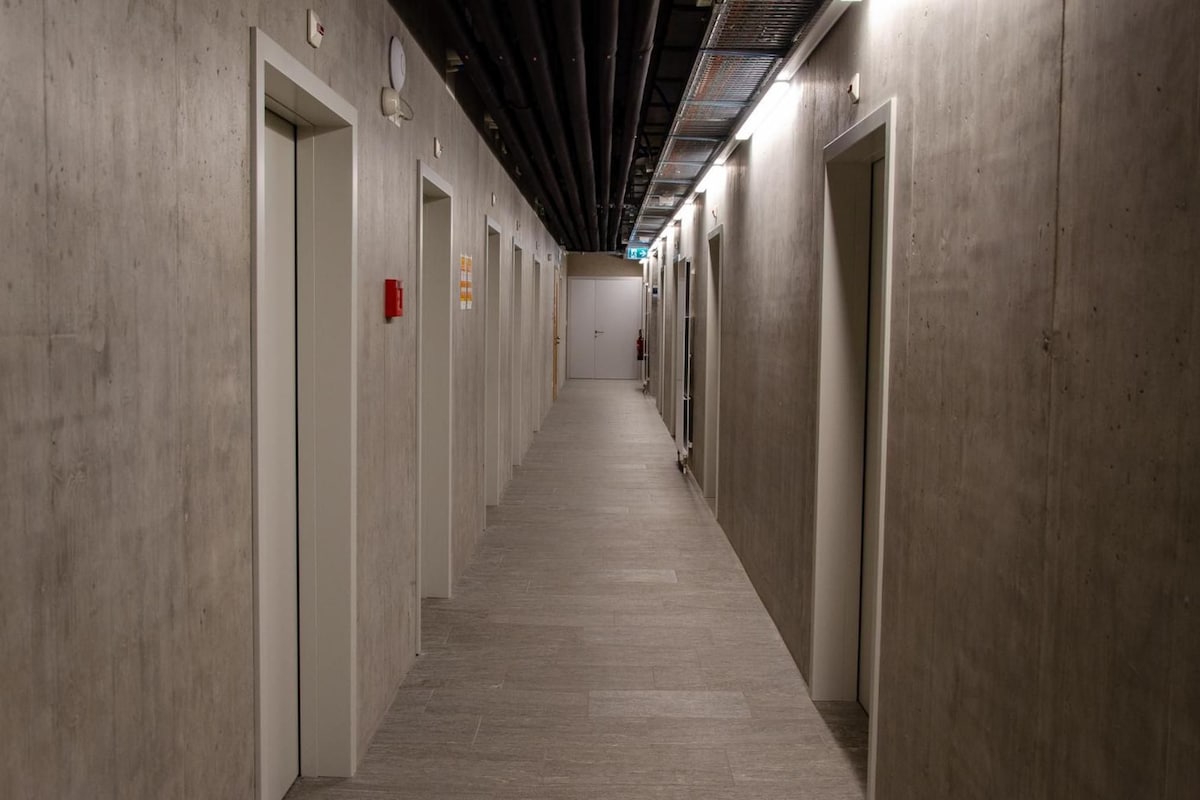 Un pasillo largo y estrecho con puertas a ambos lados, que conduce a habitaciones individuales.