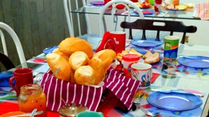 A table set with various food items, including bread, condiments, and colorful plates. - Casa Babilônia (Rio de Janeiro)
