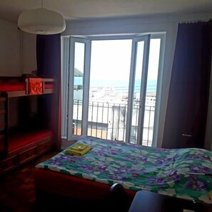 A hotel room with a bed, a small table, a bench, and a view of the sea through a balcony. - Casa Babilônia (Rio de Janeiro)