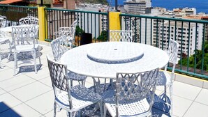 A terrace with a round table and chairs, overlooking a cityscape and the sea. - Casa Babilônia (Rio de Janeiro)