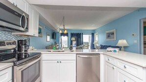 A modern kitchen with white cabinets, a stainless steel dishwasher, and a microwave. - Palace 1513 (Myrtle Beach)