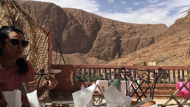Mesa al aire libre con platos de comida, vasos y vistas a un paisaje montañoso.