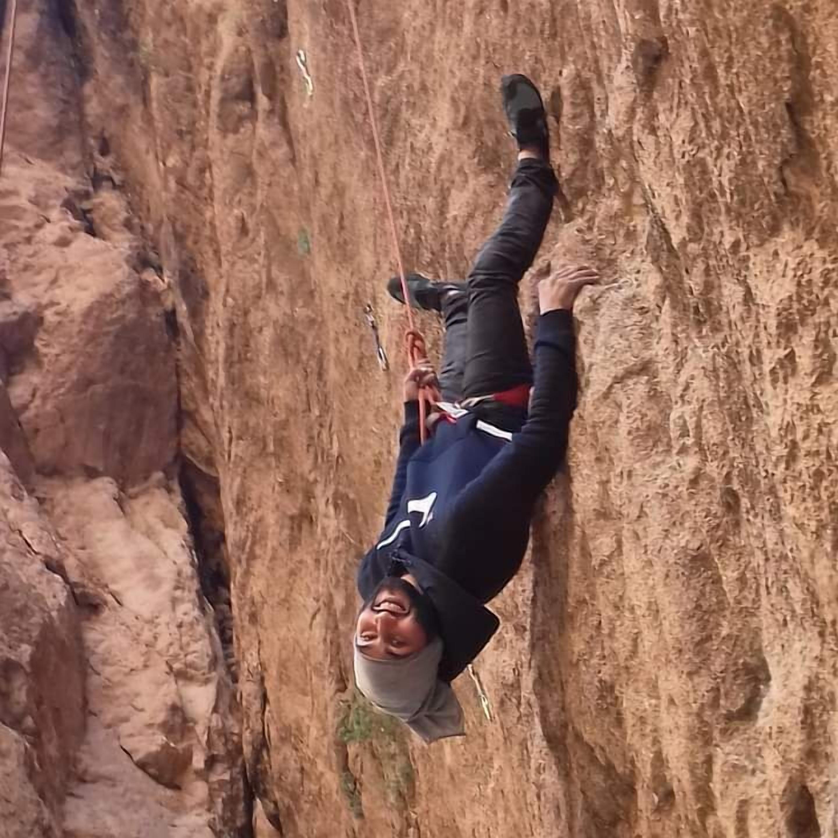 Une personne qui descend une falaise rocheuse en rappel.