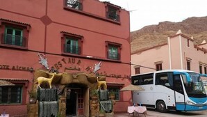 Un edificio con una entrada singular adornada con esculturas de animales y un autobús estacionado frente a él.