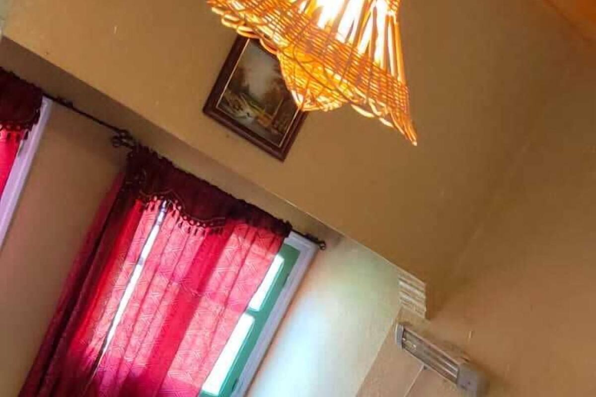 A room with two beds, a small wooden stool, a checkered floor, and a hanging light fixture.