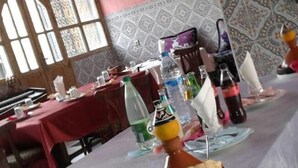 Un comedor con mesas dispuestas para una comida, un piano al fondo y paredes con diseños.