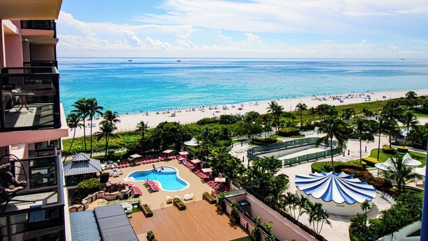A resort with a pool, beach, and palm trees.