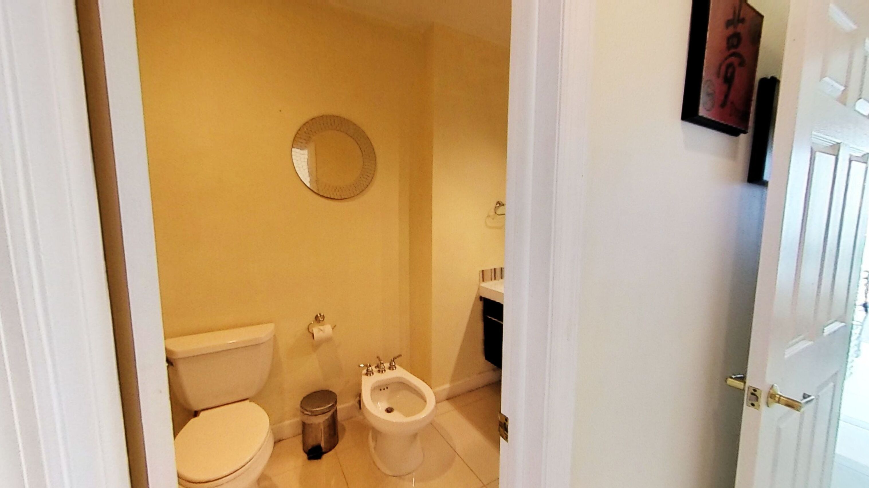 A small bathroom with a toilet, bidet, and a mirror on the wall.