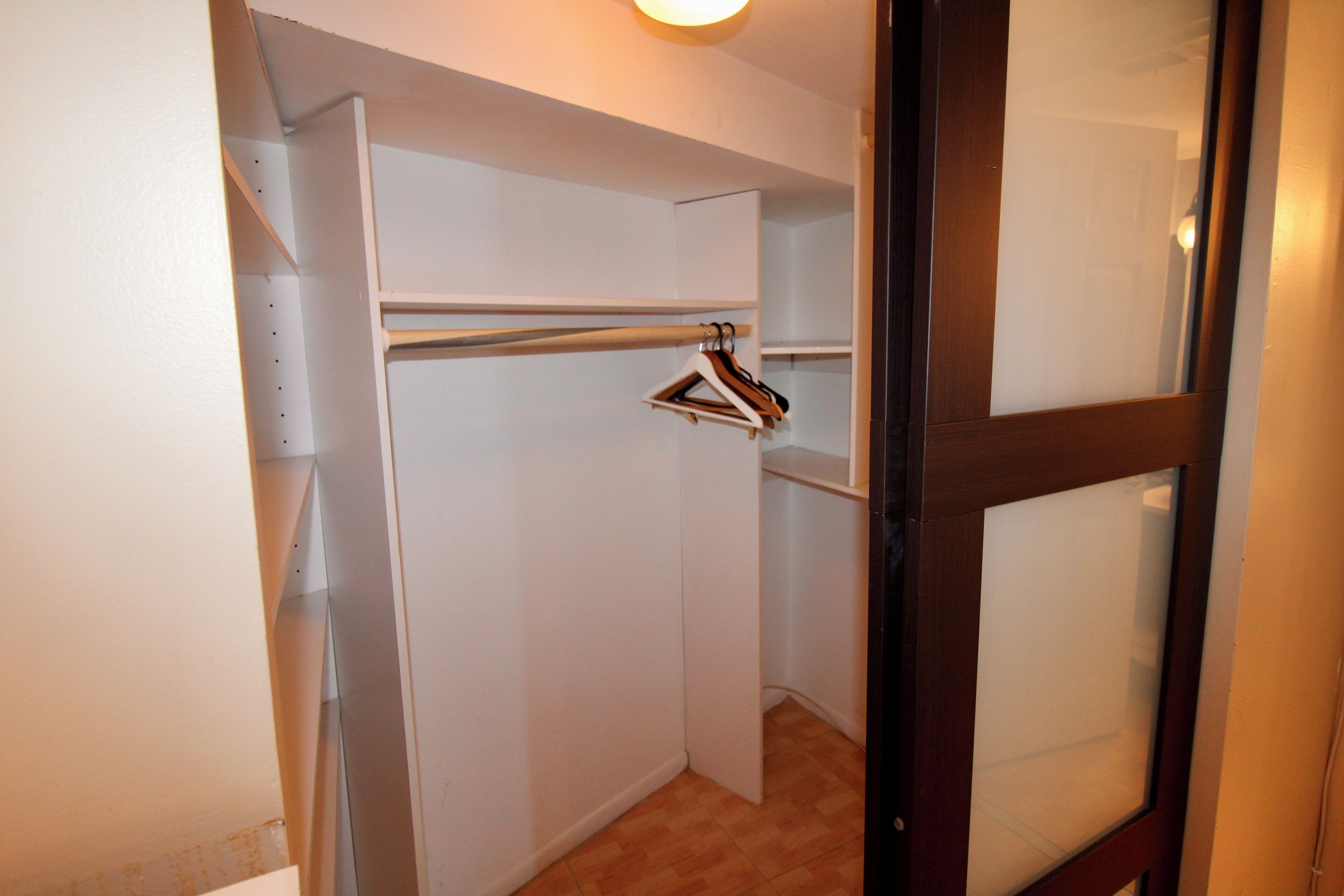 Un armario pequeño y cerrado, con puerta de madera y barra metálica para colgar ropa.