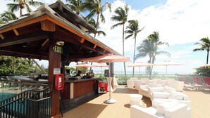 A poolside area with a bar, white cushioned seating, and umbrellas. - Alexander 1211 with Beach Access, 2 pools, sauna (Miami Beach)