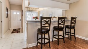 A kitchen with a bar area, three stools, and a window with curtains. - Resort-style condo - close to beaches and downtown Naples. (Naples)