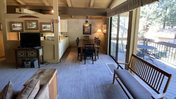 A cozy living room with a fireplace, a dining area, and a large window overlooking a deck. - Mountain Retreat.                  (Mammoth Lakes)