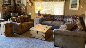 A cozy living room with a fireplace, wooden furniture, and framed pictures on the walls. - Mountain Retreat.                  (Mammoth Lakes)