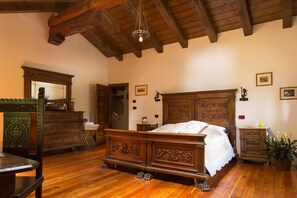 A traditional wooden bedroom with a large bed, a dresser, and a mirror.
