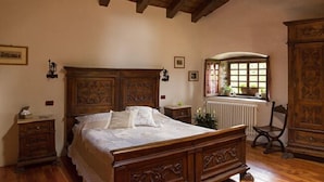 Un dormitorio con cama de madera, mesita de noche, cómoda y ventana con vista al exterior.