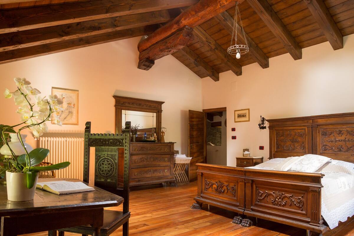 Ein traditionell eingerichtetes Schlafzimmer mit einem hölzernen Bett, einem Schminktisch und einem Schreibtisch mit Pflanze.