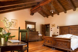 A traditional bedroom with a wooden bed, a dresser, and a desk with a plant.